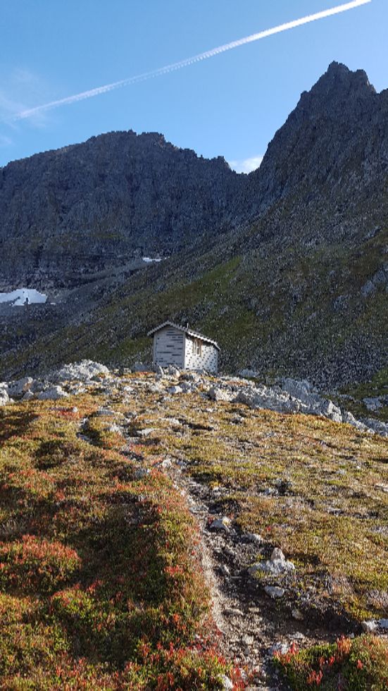 Hytta som ligger på moreneryggen foran Storevatnet. Toppen til Nordre Dalamannshorn ser en i bakgrunnen til høyre. En må sikt seg rett opp mot denne til omtrent midt på fjellesiden, deretter går en på langs under hammerene