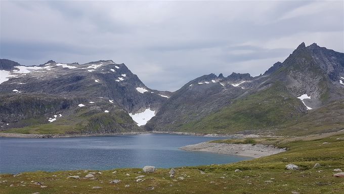 Ved Storevatnet. Stokkfonntind sees litt til høyre for midten  med Synnavindsnipa på høyre side og Tungremstindane på venstre side. Veien mot fjellet går langsvannet på høyre side.