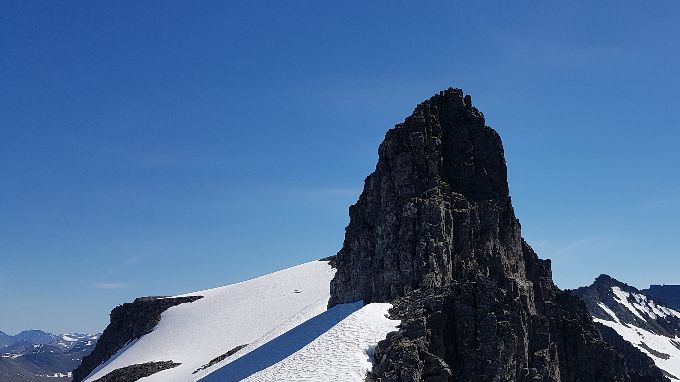 Utsikt mot sør. Toppen en ser er ikke Blåbretinden, den ligger bakom. Til høyre for denne ser en Skarrabben og den brede ryggen på Råna.