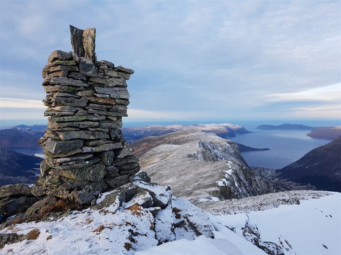 Varden på Fossholtinden. Midt i bildet ser en en forhøyning som er toppen på Grøthornet. Godøya ut i havet til høyre.