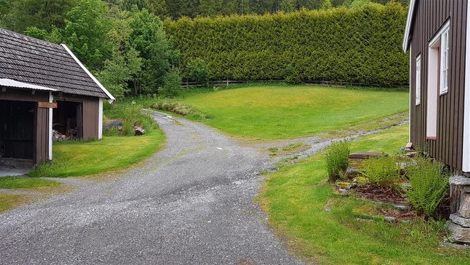 Starten på stien . Skiltet henger på garasjen. Opp til høyre