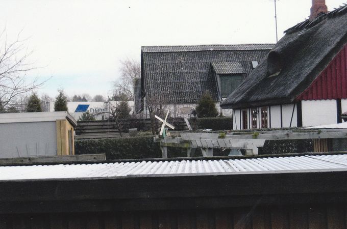 I baggrunden kan man se en kølerlastbil parkeret ved laden og i flugt linje slyngede med den lavfrekvent infralyd ind i gavlen på vores parcelhus hver morgen så bygningen rystede, glas i vinduet summede af vibrationer som en spyflue.
